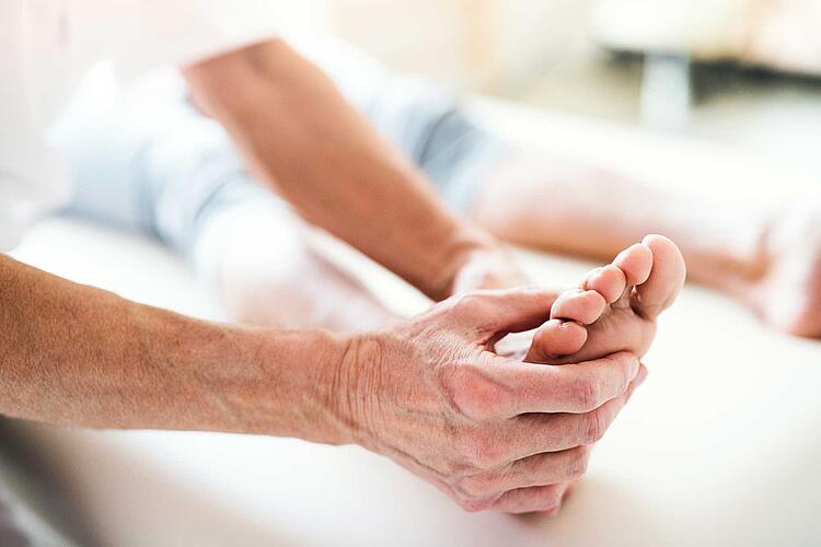 Physiotherapeut behandelt Fuß eines Patienten