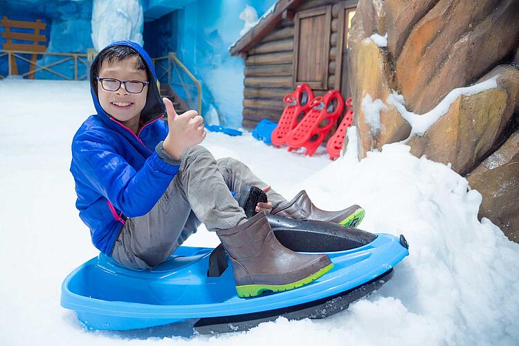 Junge auf einem Schlitten in einer Skihalle