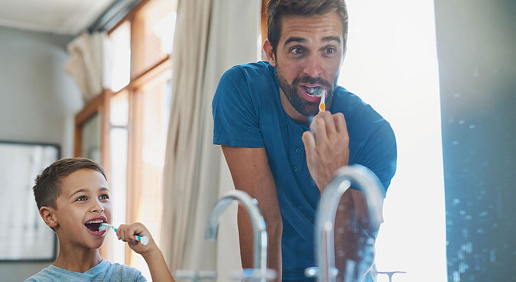 Vater und Sohn putzen sich die Zähne.