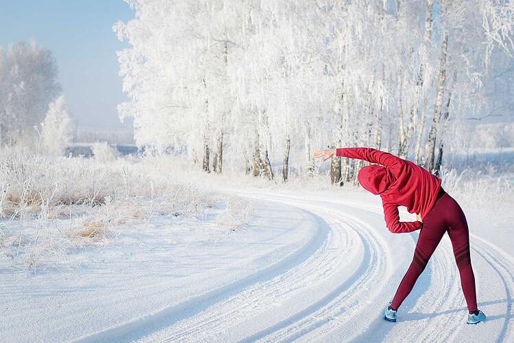 Joggerin macht Dehnübungen im Schnee