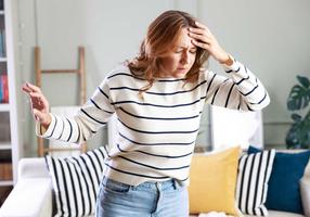 Frau ist schwindelig, sie greift sich mit der Hand an die Stirn
