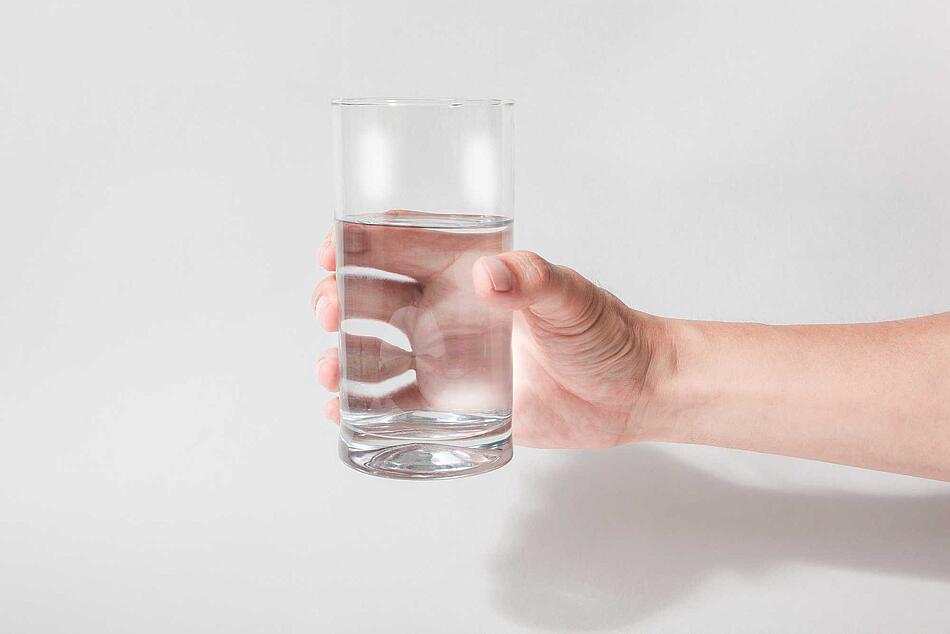 Hand hält ein Glas Wasser 
