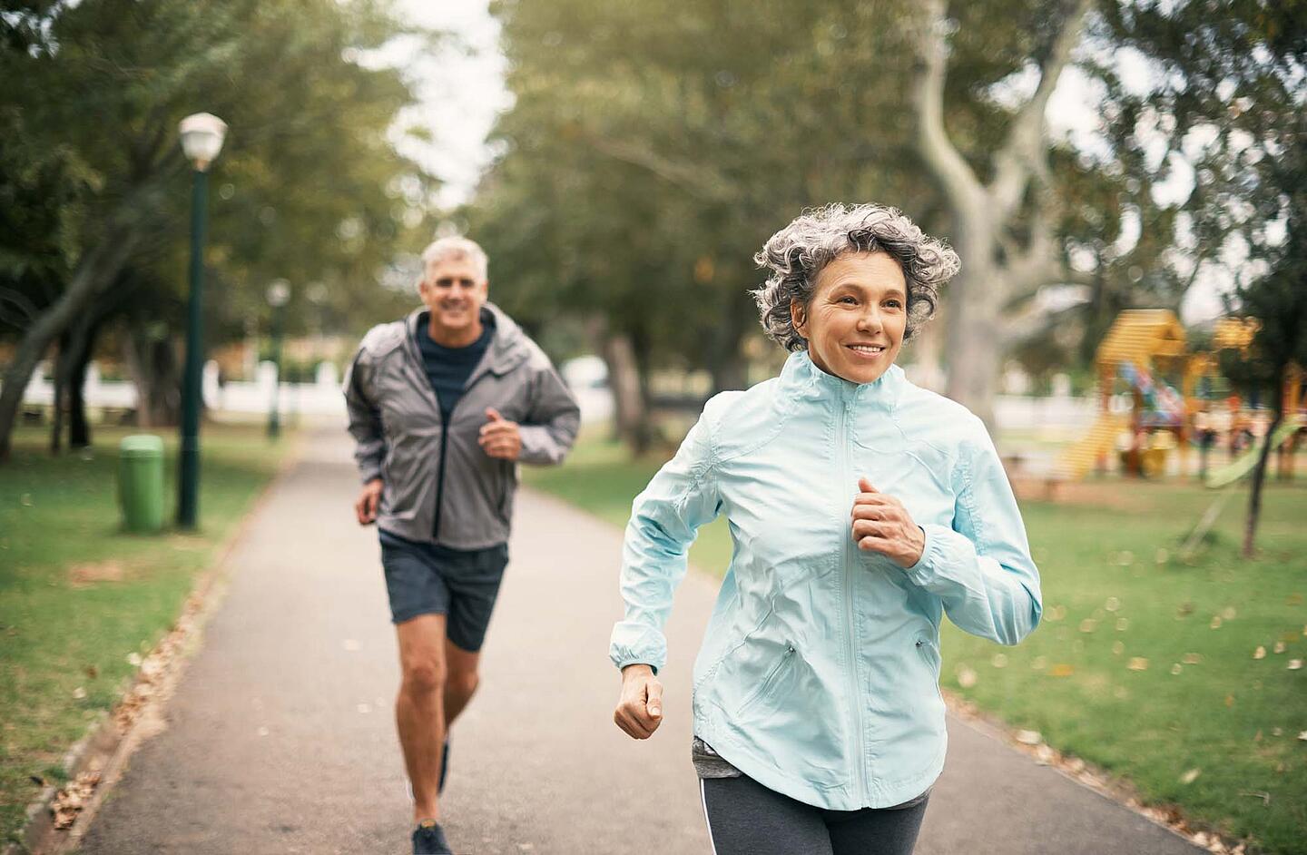 Eine Frau und ein Mann beim Joggen im Park.