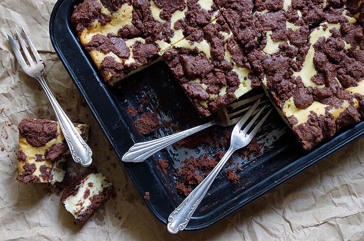 Kuchen auf einem Kuchenblech, drei Stücke fehlen und dort liegen Gabeln.