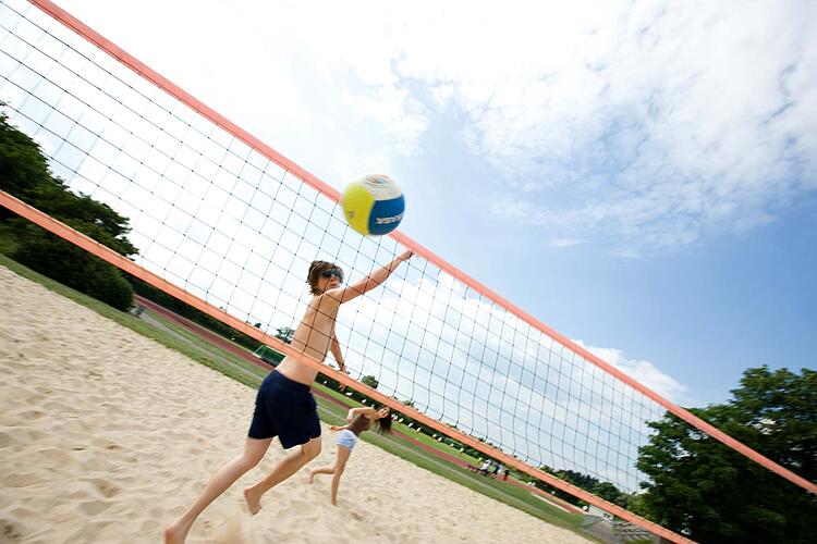 Jugendliche spielen Beachvolleyball.