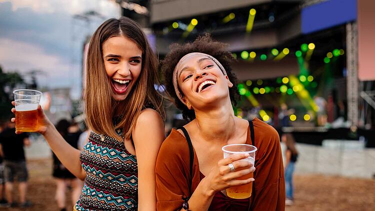 Zwei Freundinnen trinken zusammen ein Bier auf einem Fest