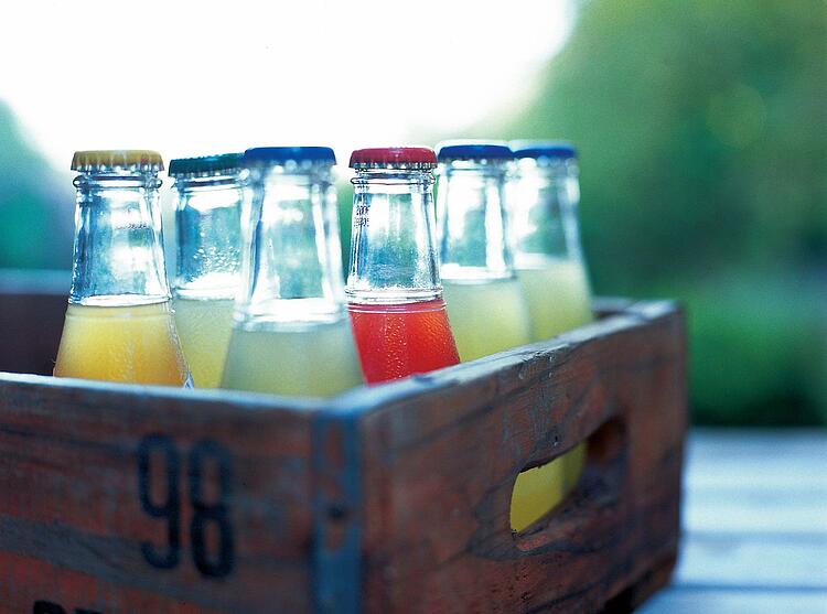 Glasflaschen mit Limonade in einer Holzkiste.