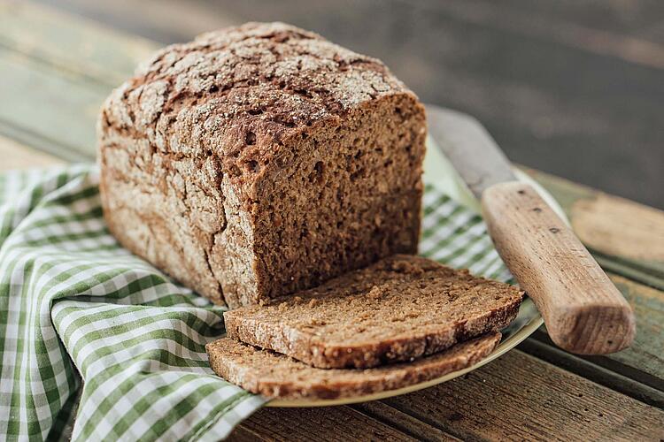 Vollkornbrot in Scheiben geschnitten auf einem grün-weiß karierten Tuch.