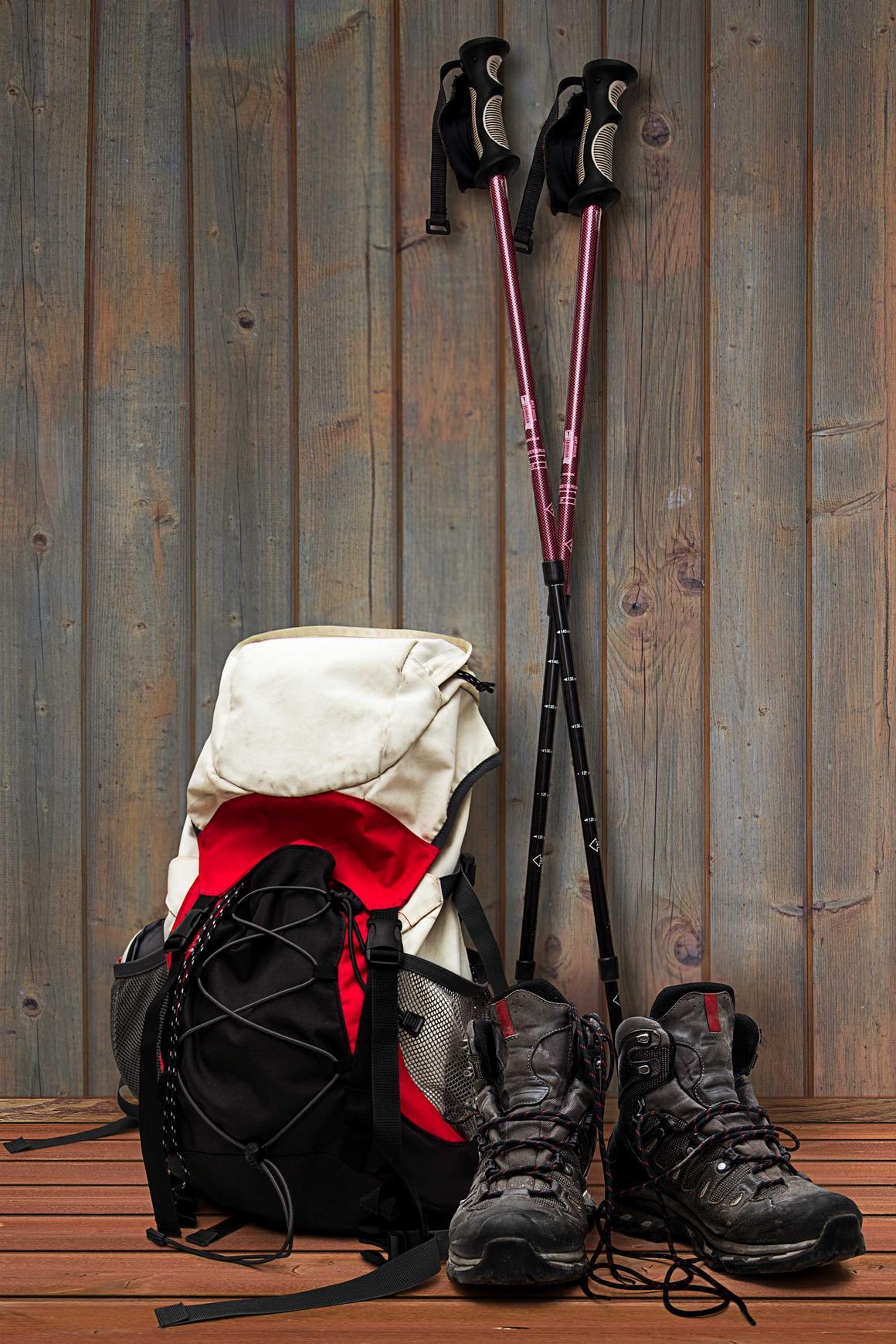 Bildnachweis: © stock.adobe.com / triskelant Wanderrucksck, Wanderschuhe und Wanderstöcke lehnen an einer Holzwand