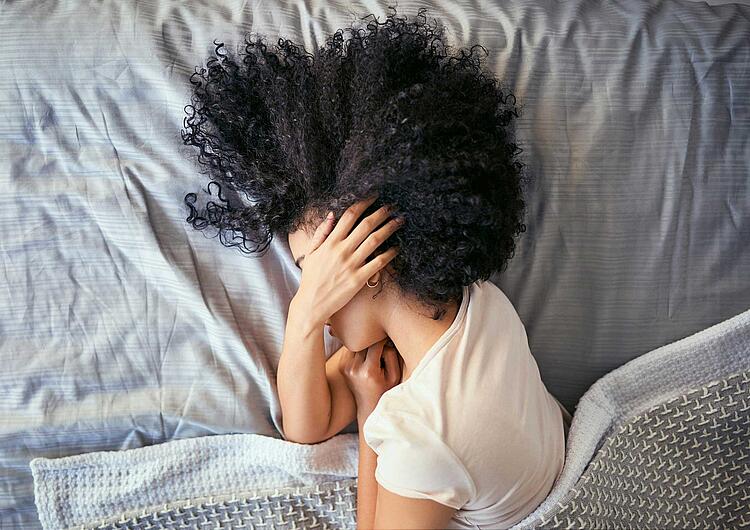 Frau liegt mit Kopfschmerzen im Bett