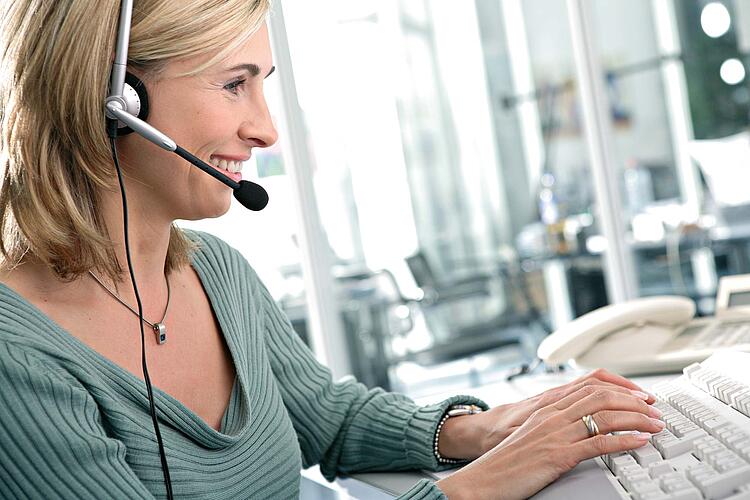 Frau mit Headset am Computer.