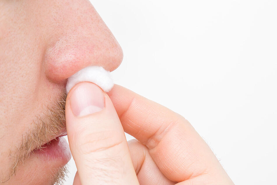 Ein Mann steckt Watte in seine Nase, um Nasenbluten zu stoppen.