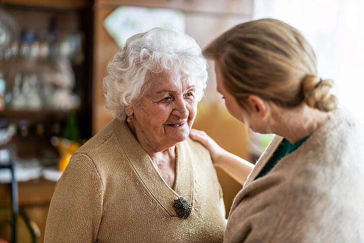 Pflegerin legt Seniorin die Hand auf die Schulter