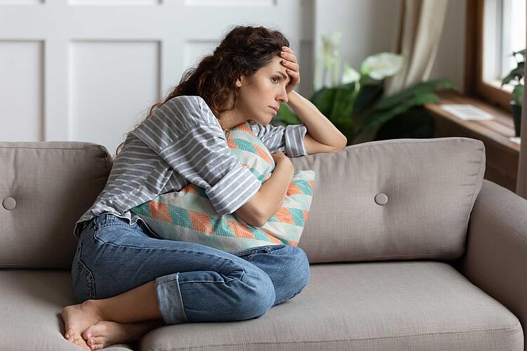 Frau sitzt erschöpft auf dem Sofa