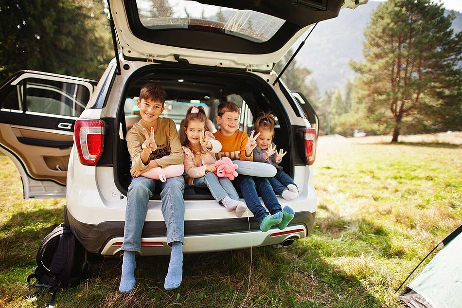 Vier Kinder sitzen im Kofferraum eines Autos