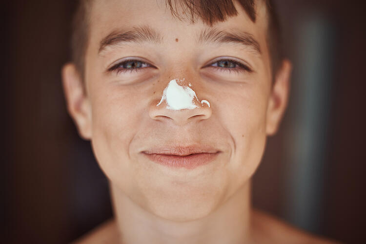 Junge mit einem Klecks Sonnenmilch auf der Nase