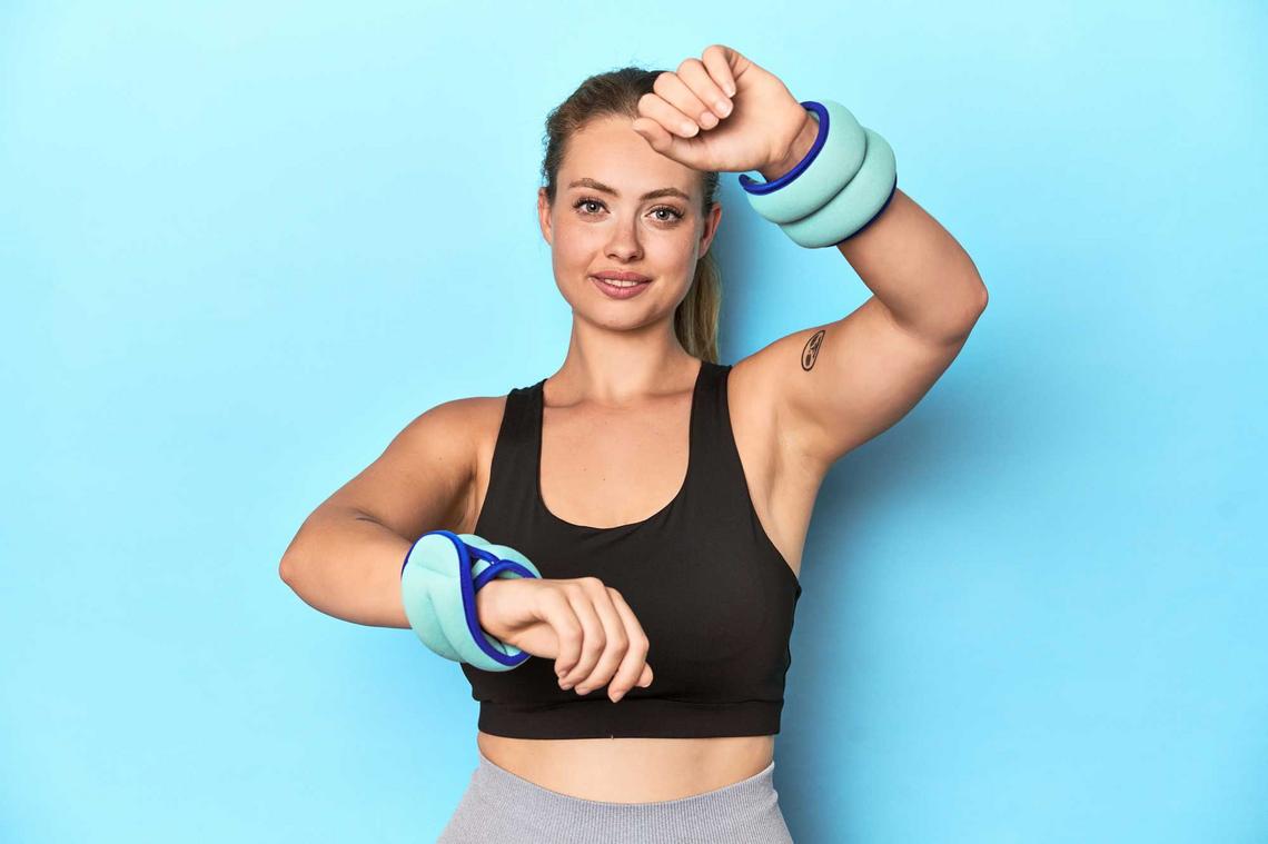Sportliche Frau trägt Gewichtsmanschetten an den Armen
