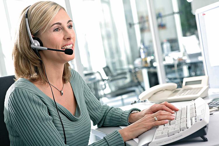 Frau mit Headset am Computer.