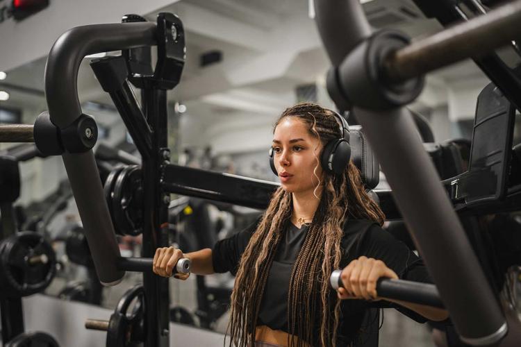 Junge Frau macht Übungen an einer Brustpresse im Fitnessstudio