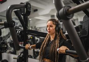 Junge Frau macht Übungen an einer Brustpresse im Fitnessstudio