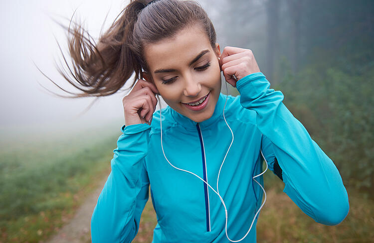 Junge Frau mit Kopfhörern beim Joggen.