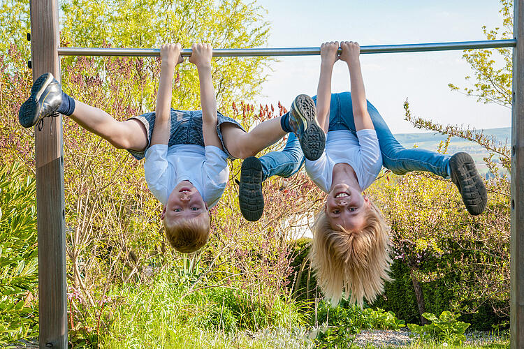 Kinder turnen auf dem Spileplatz an einer Stange