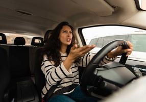 Wütende Frau gestikuliert wild im Auto
