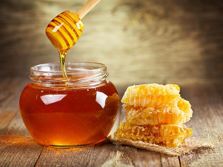 Honig im Glas daneben Honigwaben