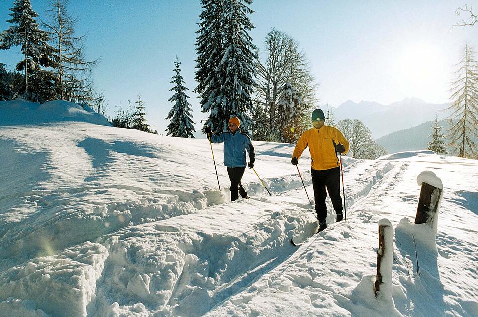 Zwei Personen beim Skilanglaufen im Sonnenschein.