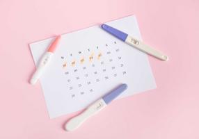 Schwangerschaftstests liegen auf einem Kalenderblatt auf dem die letzte Menstruation eingetragen ist