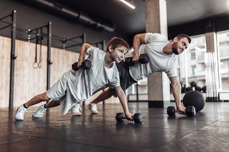 Krafttraining für Kinder: Vater und Sohn trainieren im Fitnessstudio