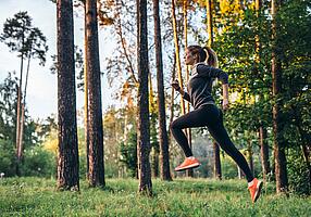 Junge Frau joggt im Wald.