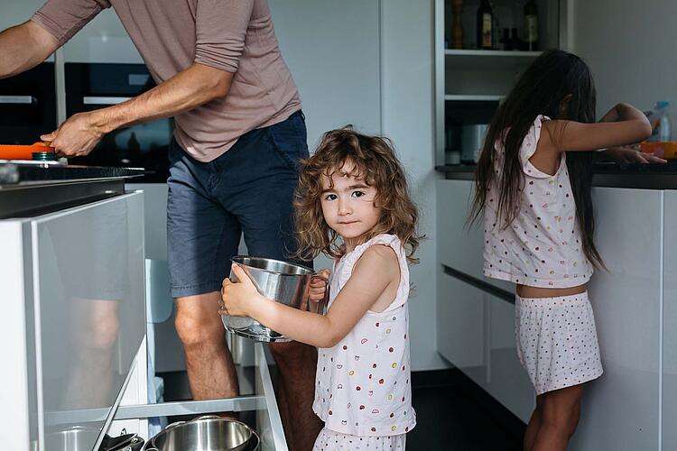 Ein kleines Mädchen hilft ihrem Vater in der Küche.