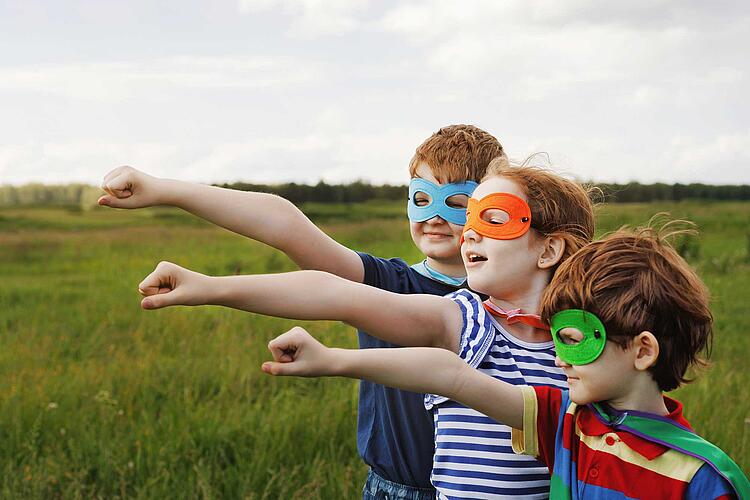 Kinder mit Masken spielen Supeerhelden