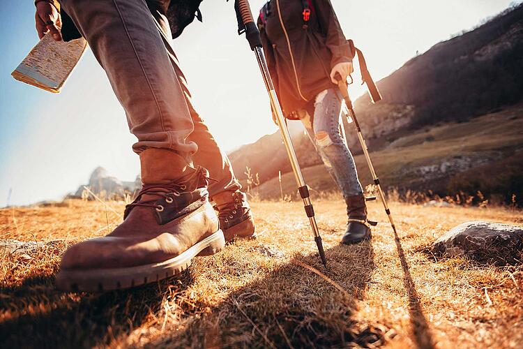 Paar mit wWnderschuhen und Wanderstöcken auf einer herbstlichen Wiese