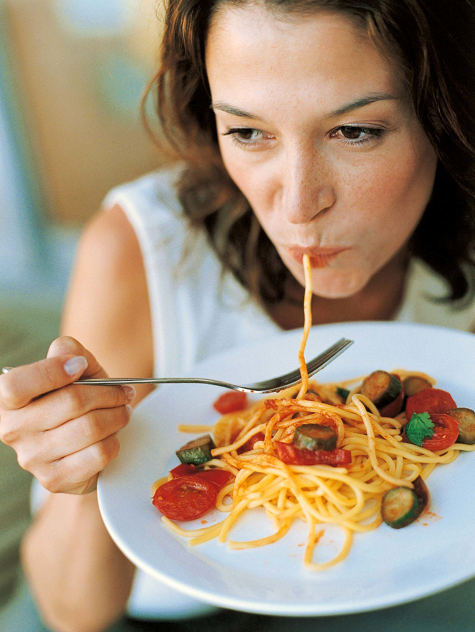 Eine Frau hält einen Teller mit Spaghetti in der Hand und isst. - Bildnachweis: © wdv / Jan Lauer Eine Frau hält einen Teller mit Spaghetti in der Hand und isst.