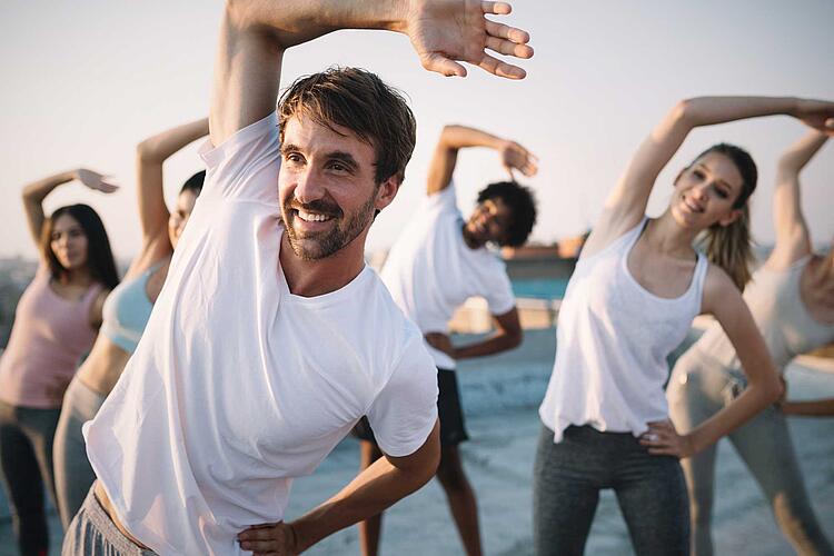 Gruppe macht gemeinsam Fitnessübungen im Freien