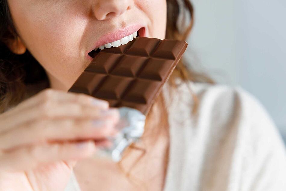 Frau beisst in eine Tafel Schokolade