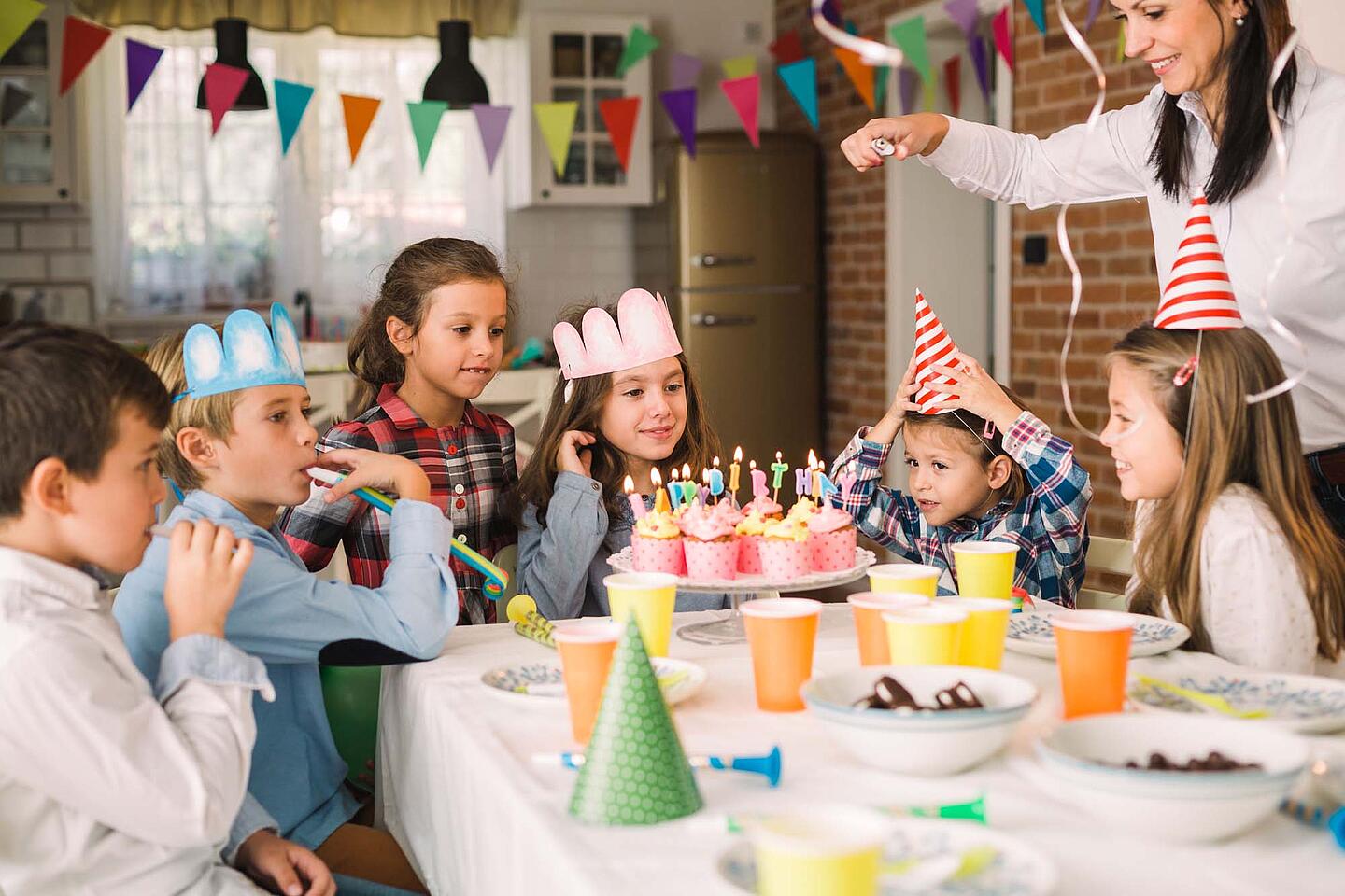 Kinder sitzen am Tisch und feiern Kindergeburtstag.