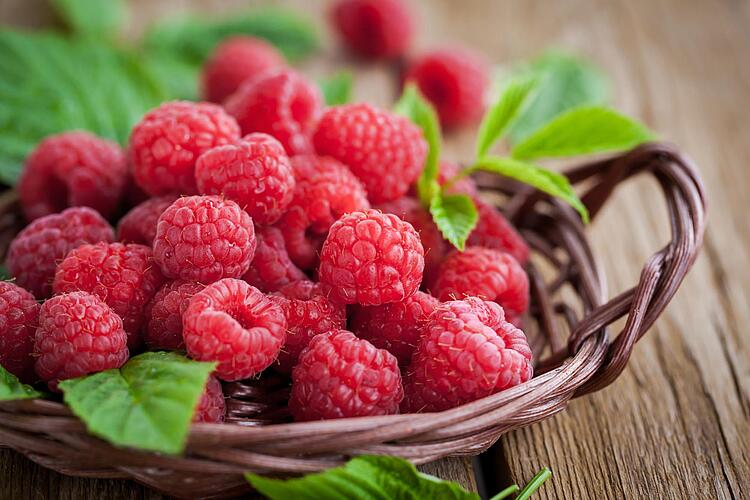 Himbeeren in einem Korb auf einem Holztisch