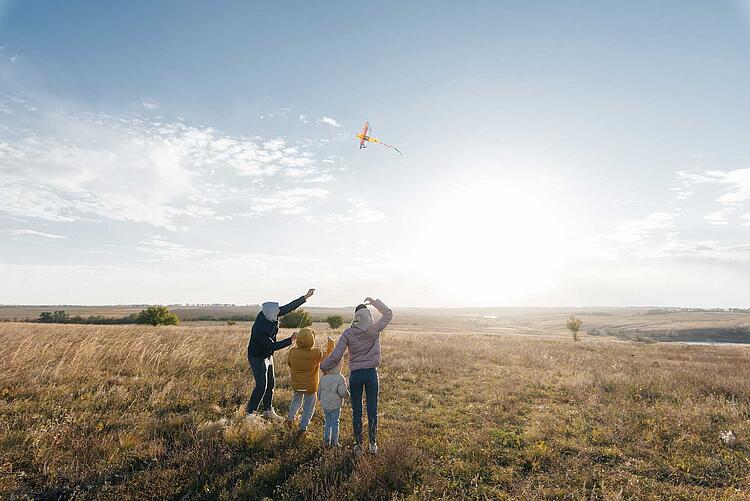 Familie auf einer Wiese lässt im Herbst Drachen steigen