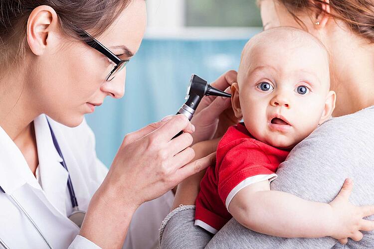 Ärztin untersucht Baby im Ohr