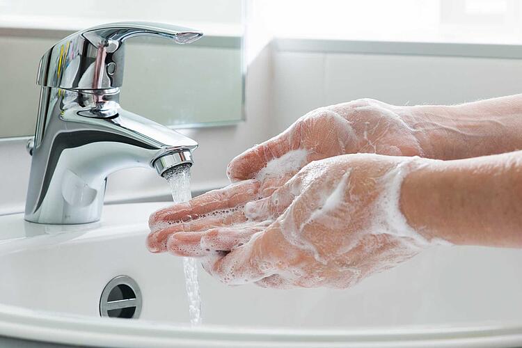 Eingeseifte Hände unter einem laufenden Wasserhahn