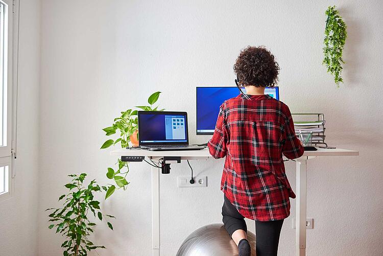 Frau arbeitet zu Hause an einem Stehschreibtisch