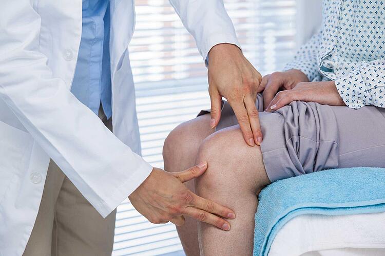 Arzt untersucht das Knie einer Patientin