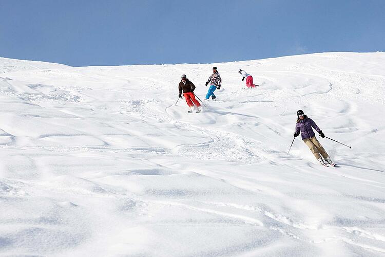 Gruppe von Skifahrern auf einer Skipiste bei der Abfahrt.