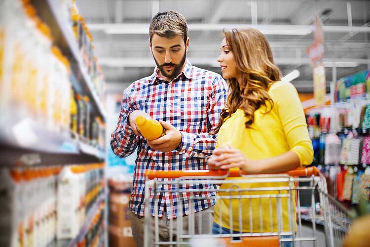 Paar kauft Orangensaft ein und prüft dabei die Inhaltsstoffe