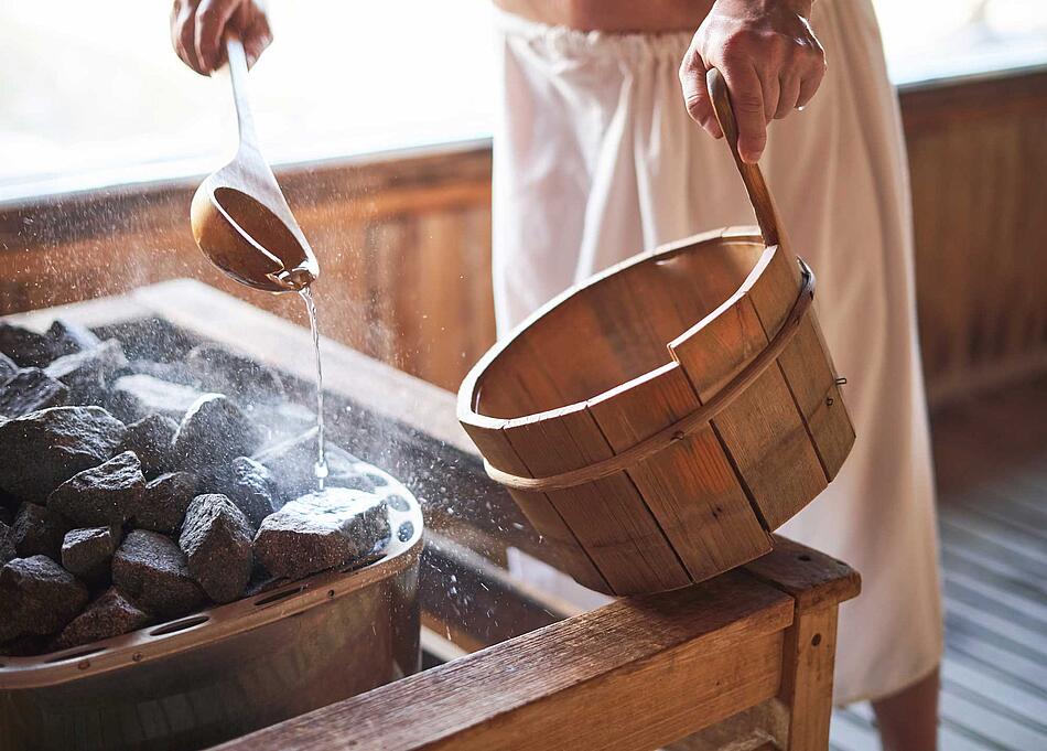 Mann macht in der Sauna einen Aufguss