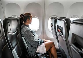 Reisethrombose: Frau sitzt im Flugzeug Reisethrombose: Frau sitzt im Flugzeug