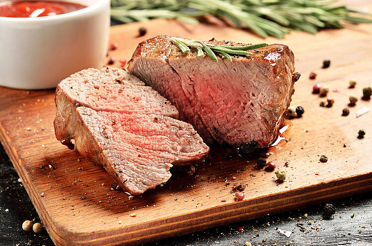 Rinderfilet mit Rosmarin und Pfeffer auf einem Holzbrett.